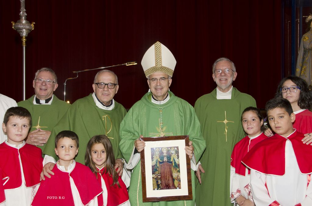 Il Vescovo mostra il quadro che gli è stato regalato, attorniato dai concelebranti e dai ministranti